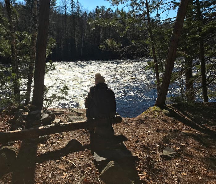 Woman sitting by the Dumoine River